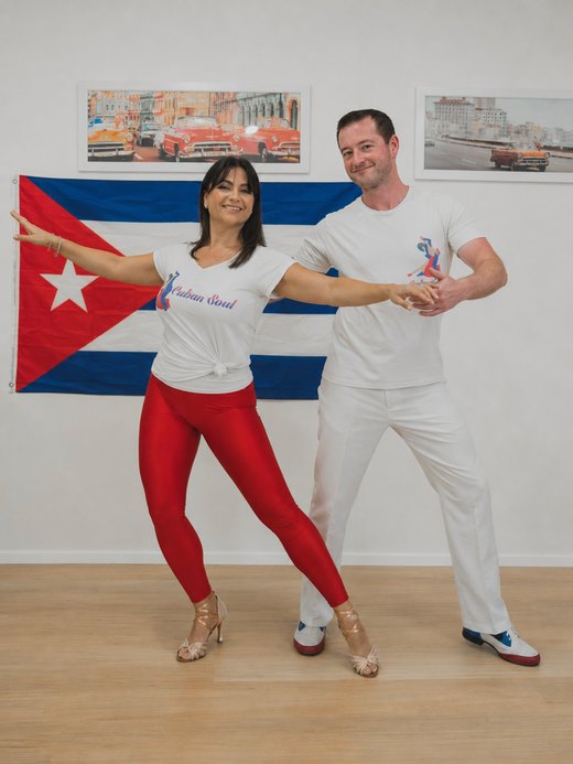 Nikoletta and Stephen dancing in front of a Cuban flag