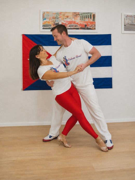 Nikoletta and Stephen dancing in front of a Cuban flag