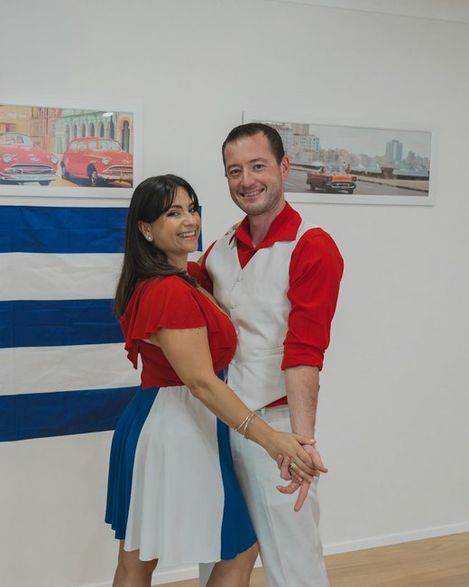 Nikoletta and Stephen hand in hand in front of a Cuban flag