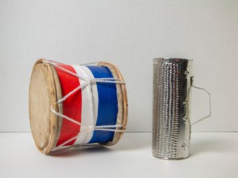 A tambora drum painted in the Dominican flag colours, beside a metal güira