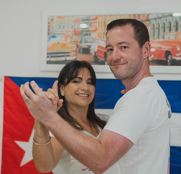 Stephen and Nikoletta dancing in front of a Cuban flag